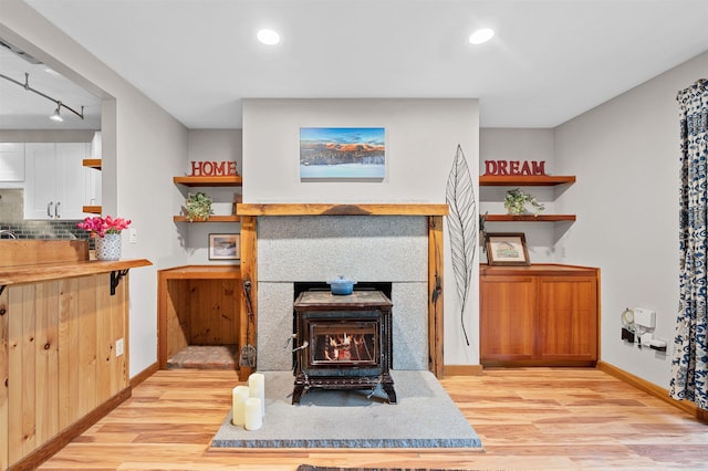 living room with light wood-type flooring, baseboards, track lighting, a wood stove, and recessed lighting