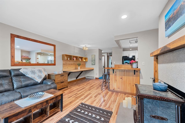 living area with light wood-style floors, a baseboard heating unit, and baseboards