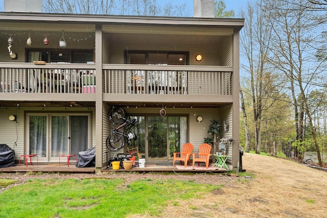 back of house with a balcony and a chimney