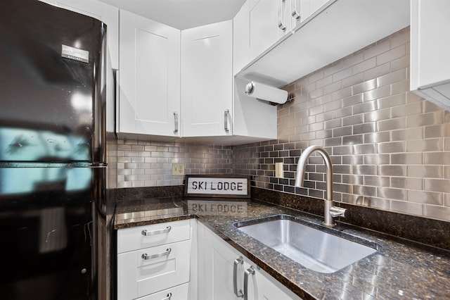 kitchen with freestanding refrigerator, a sink, tasteful backsplash, and white cabinetry