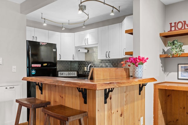 kitchen featuring backsplash, white cabinetry, a kitchen breakfast bar, open shelves, and a sink