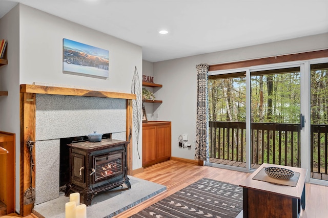 living room with a wood stove, wood finished floors, recessed lighting, and baseboards