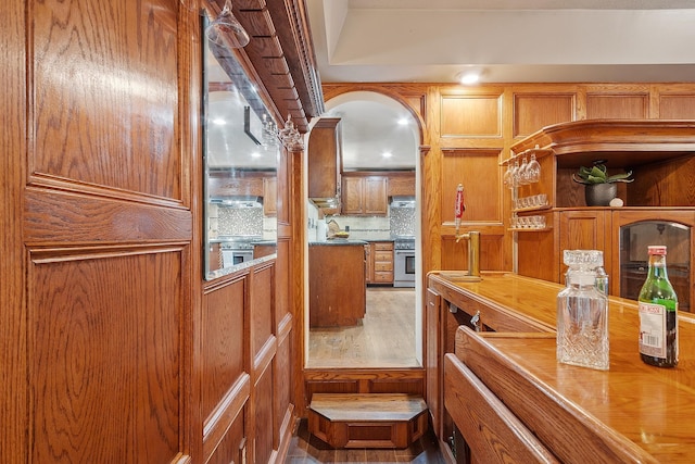 kitchen featuring backsplash, brown cabinets, a sink, and high end stainless steel range