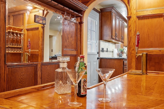 bar area with arched walkways and wood finished floors
