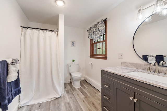 bathroom featuring a baseboard radiator, wood finished floors, toilet, vanity, and baseboards