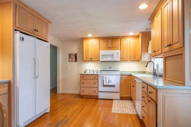 kitchen featuring white appliances, a sink, recessed lighting, light countertops, and light wood-style flooring
