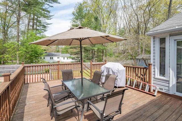 wooden deck with outdoor dining space, a grill, fence, and view of scattered trees