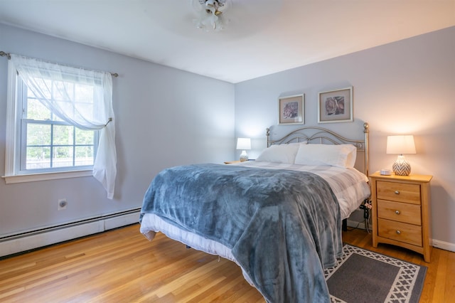 bedroom with wood finished floors and a baseboard heating unit