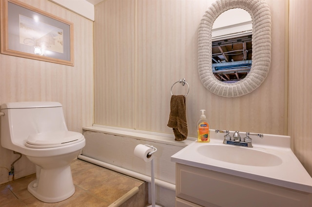 half bathroom featuring toilet, tile patterned floors, vanity, and wallpapered walls