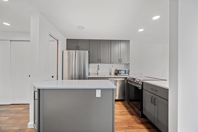 kitchen featuring stainless steel appliances, gray cabinets, light wood finished floors, light countertops, and a sink