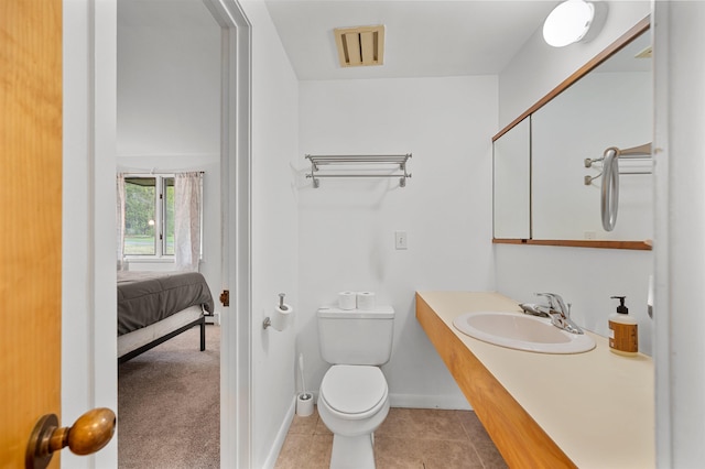 ensuite bathroom featuring toilet, vanity, tile patterned flooring, and baseboards