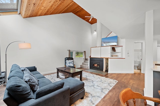 living room with wood ceiling, a fireplace with flush hearth, wood finished floors, high vaulted ceiling, and baseboards