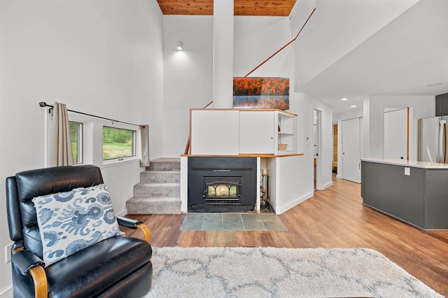living area featuring a towering ceiling, light wood-style flooring, stairway, baseboards, and recessed lighting