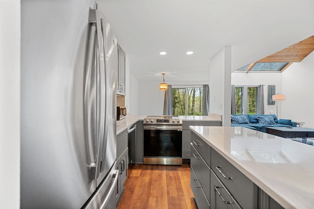 kitchen featuring appliances with stainless steel finishes, gray cabinetry, light countertops, dark wood finished floors, and recessed lighting