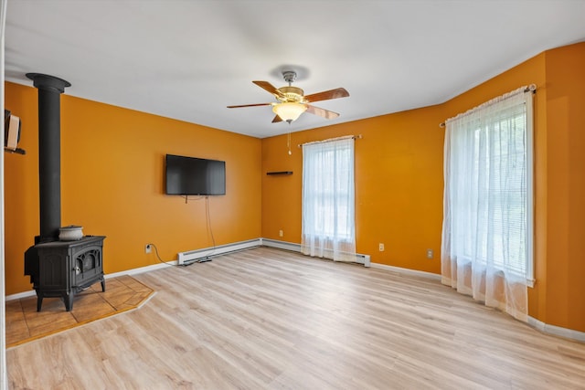 56 Call Rd, Webster, NH 03303 - unfurnished living room featuring a wood stove, wood finished floors, a ceiling fan, baseboards, and a baseboard heating unit