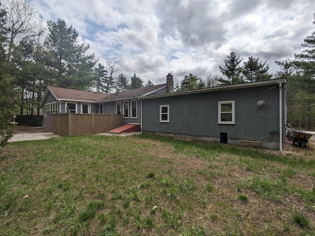rear view of house featuring a chimney and a lawn