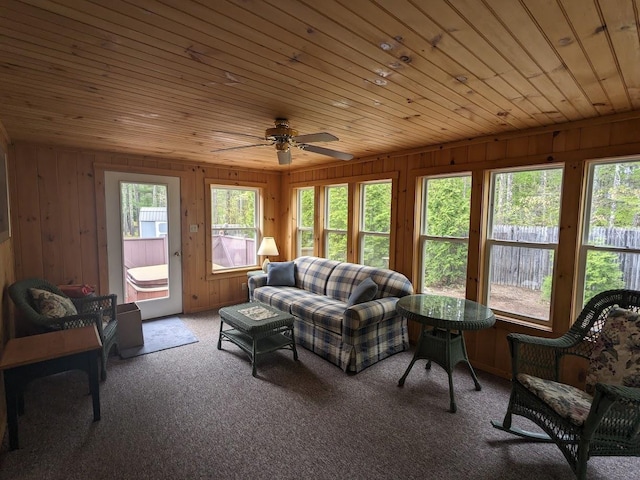 living room featuring carpet, wooden ceiling, wood walls, and a ceiling fan