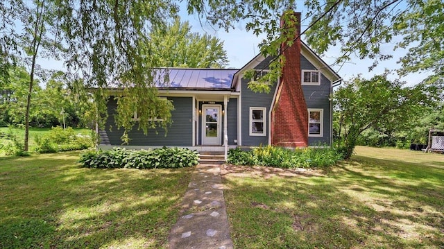 view of front of property with a front yard, a chimney, and metal roof