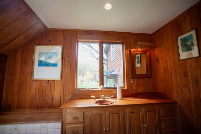 bathroom featuring wood walls, vanity, and vaulted ceiling
