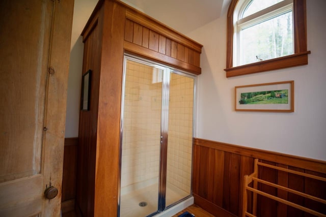 bathroom featuring a wainscoted wall and a stall shower