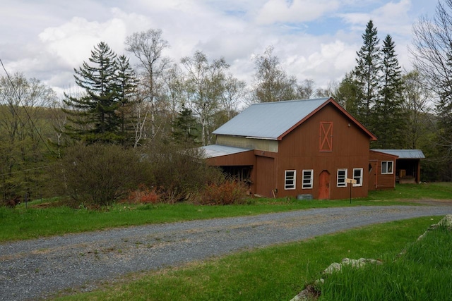 view of side of property featuring gravel driveway, metal roof, an outdoor structure, and a barn
