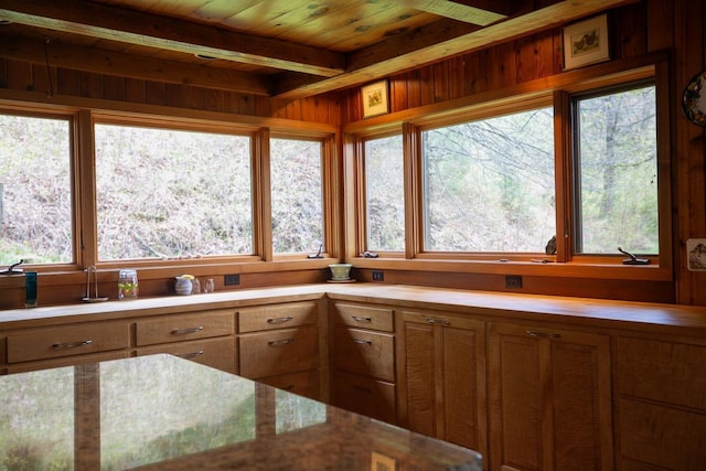 kitchen featuring plenty of natural light, brown cabinetry, beam ceiling, and wood ceiling