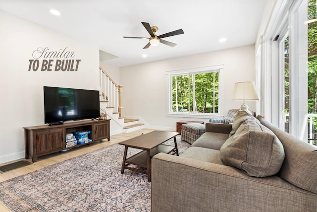 living room featuring light wood finished floors, a ceiling fan, baseboards, stairs, and recessed lighting