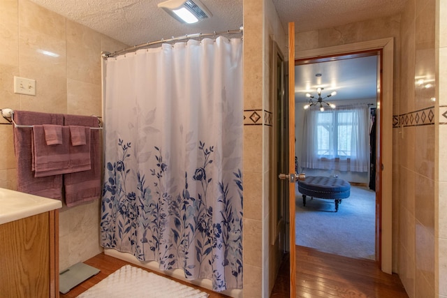 7206 S Wheelock Rd, Wheelock, VT 05851 - bathroom with tile walls, wood finished floors, curtained shower, a textured ceiling, and vanity