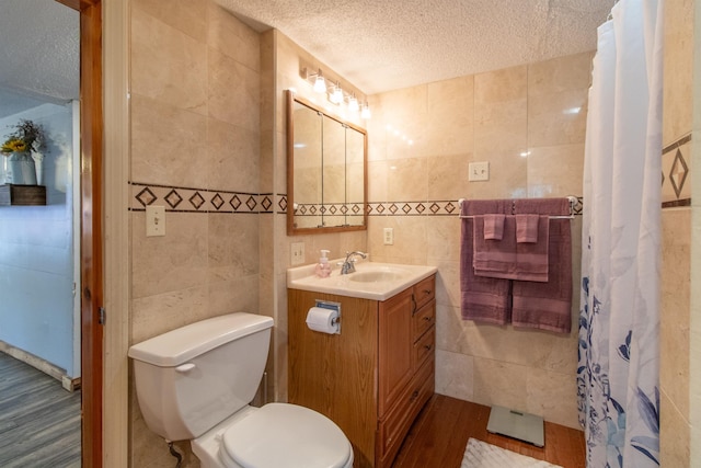 7206 S Wheelock Rd, Wheelock, VT 05851 - full bath with tile walls, a textured ceiling, toilet, vanity, and wood finished floors