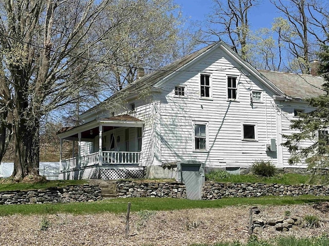 view of property exterior featuring a chimney and covered porch
