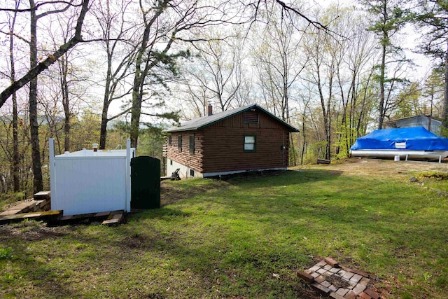 view of side of home with a chimney, log exterior, and a yard