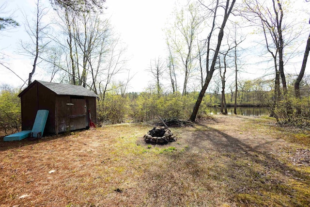 view of yard featuring a shed, an outdoor fire pit, and an outdoor structure