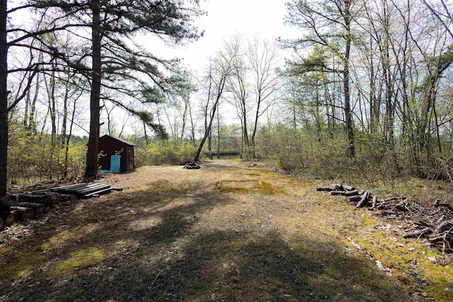 view of yard with a shed, an outbuilding, and a wooded view