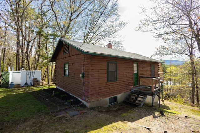 view of property exterior with log exterior, a chimney, and fence