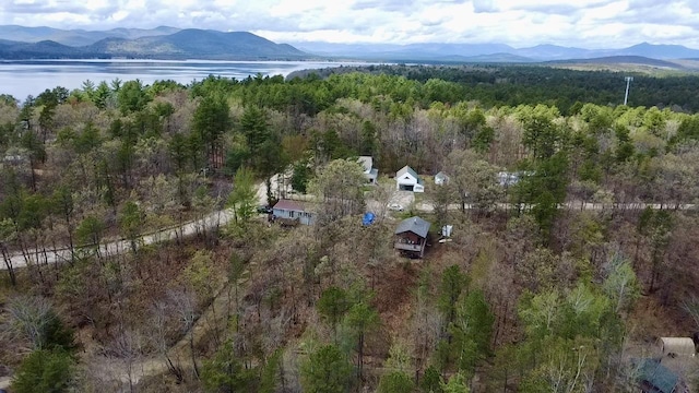 aerial view of property and surrounding area featuring a heavily wooded area and a water and mountain view