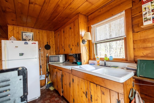 kitchen featuring white appliances, wooden ceiling, light countertops, wooden walls, and brown cabinetry