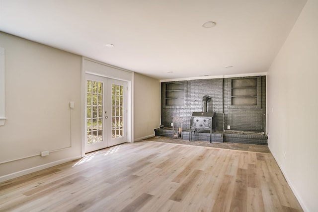 unfurnished living room featuring wood finished floors, french doors, baseboards, and built in features