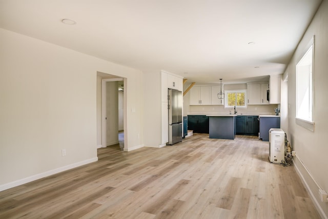 unfurnished living room with light wood finished floors, baseboards, and a sink