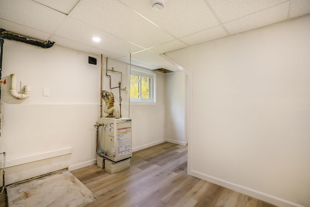 basement featuring wood finished floors, a drop ceiling, and baseboards