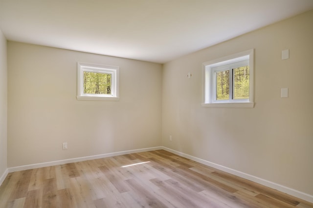 unfurnished room with plenty of natural light, light wood-type flooring, and baseboards