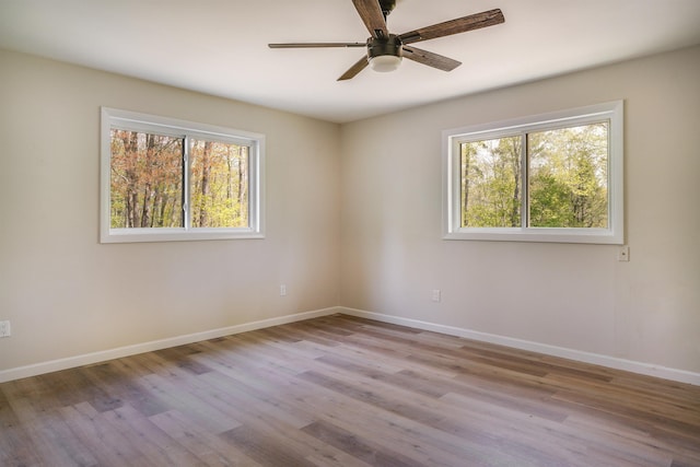 spare room featuring plenty of natural light, baseboards, and wood finished floors