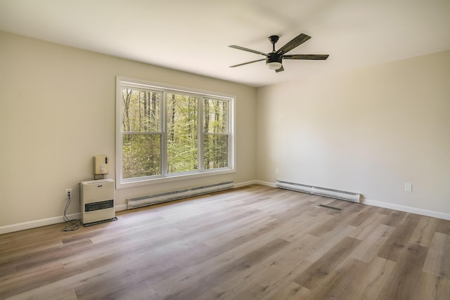 empty room with a baseboard heating unit, ceiling fan, wood finished floors, and baseboards