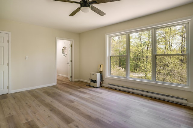 spare room featuring a baseboard radiator, a ceiling fan, wood finished floors, and baseboards
