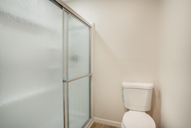 bathroom featuring an enclosed shower, wood finished floors, and toilet