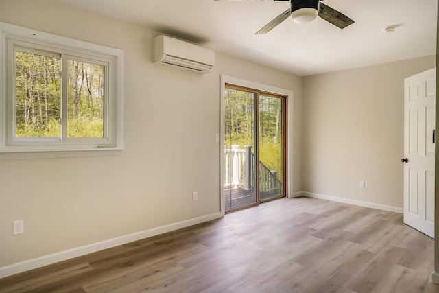 empty room featuring a wall unit AC, healthy amount of natural light, and light wood-style flooring