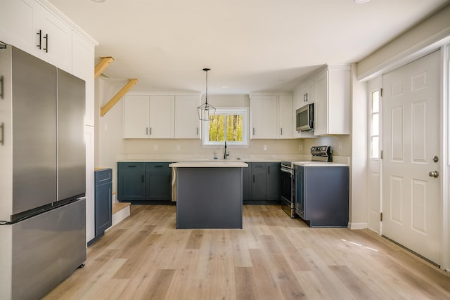 kitchen featuring stainless steel appliances, light wood-style floors, a kitchen island, and white cabinetry