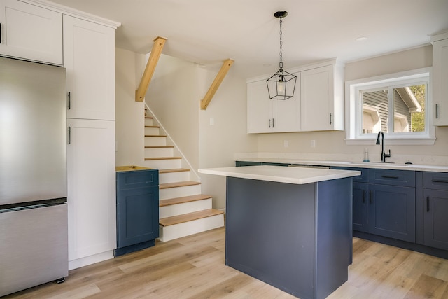 kitchen with stainless steel refrigerator, a sink, a center island, and light wood-type flooring
