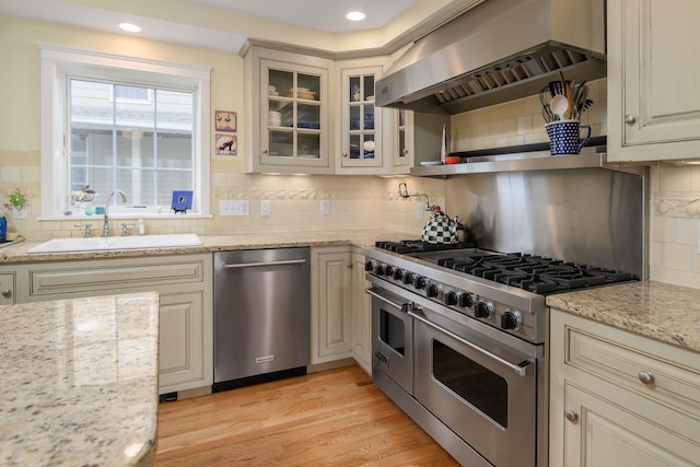 150 Webhannet Dr, Wells, ME 04090 - kitchen with appliances with stainless steel finishes, wall chimney range hood, a sink, tasteful backsplash, and light stone countertops