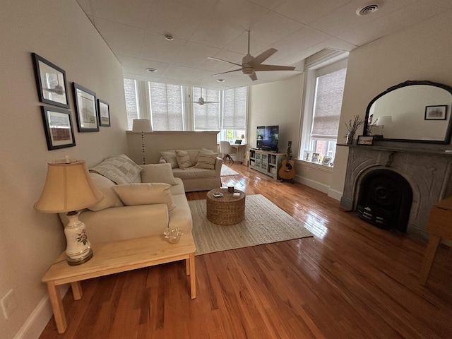 living area featuring plenty of natural light, baseboards, ceiling fan, and wood finished floors