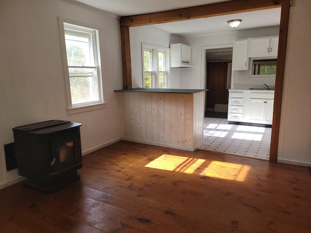 kitchen with a wood stove, white cabinetry, wood finished floors, healthy amount of natural light, and crown molding
